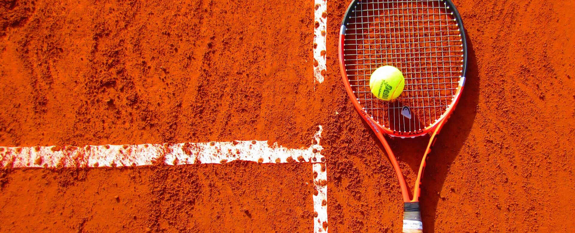 Tennis racket and ball on a red clay court